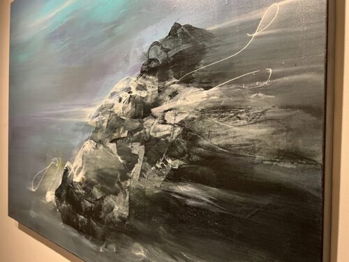 Close-up of From Ancient Beginnings by Patricia Gagic - faceted black and slate rock struck with chalk white under a teal sky